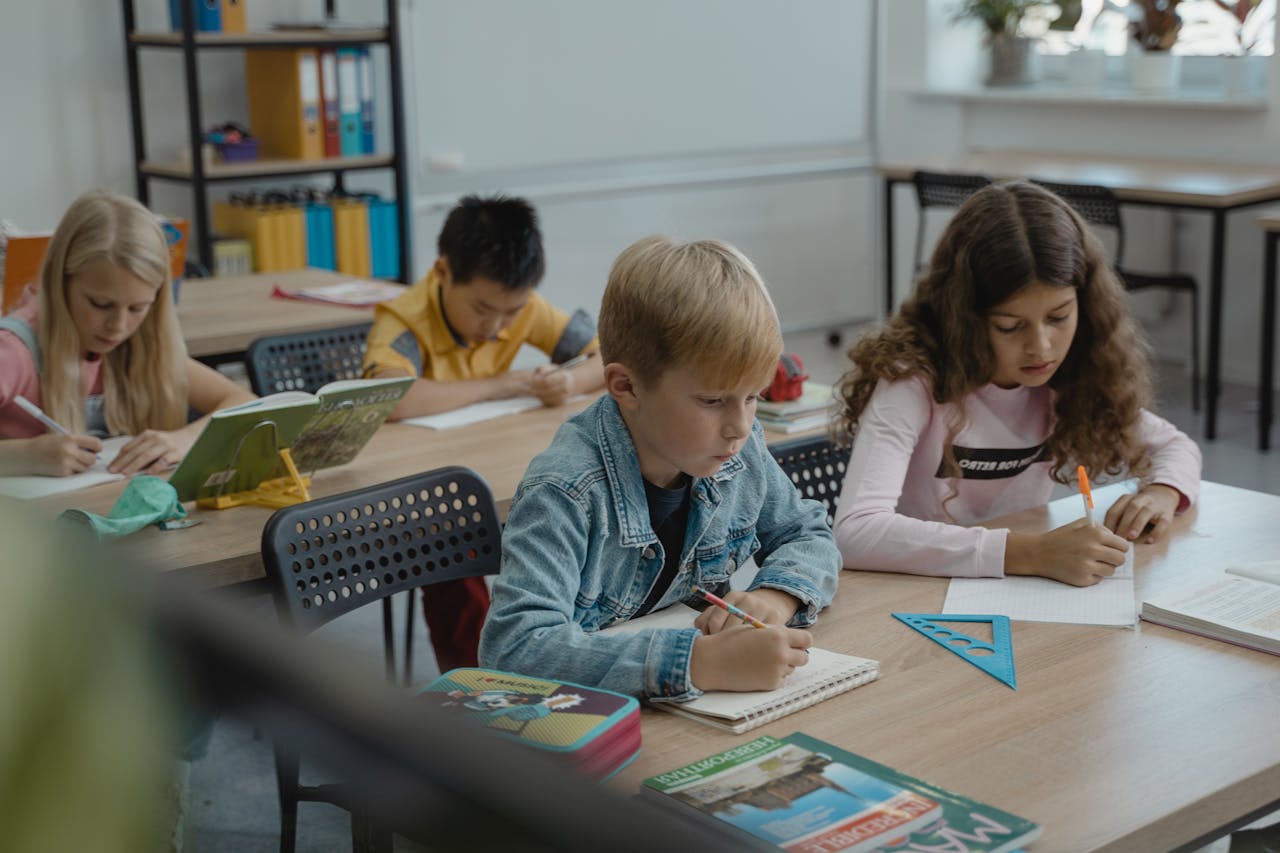 A group of children focused on studying in a classroom with books and stationery.
