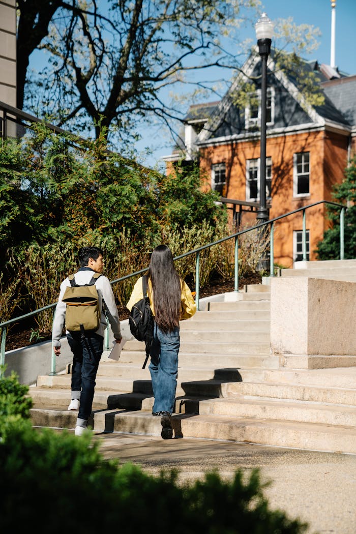 team-04 Two young adults walking up outdoor stairs surrounded by greenery and buildings.