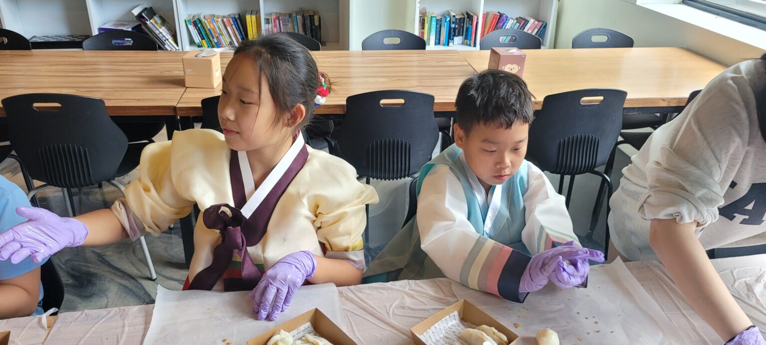 Students in hanbok shaping songpyeon rice cakes