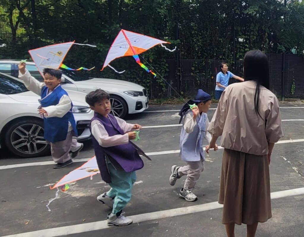 Students in hanbok flying their kites outside